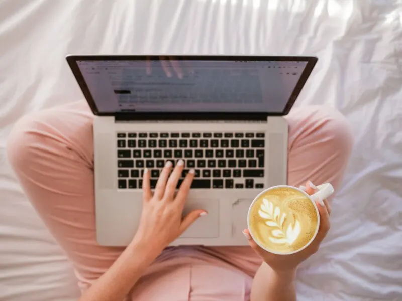 woman sitting cross legged with laptop and a latte -- If you're looking to take your brand to the next level, you want the right tools to get there. We're sharing the best productivity tools for your toolbox.